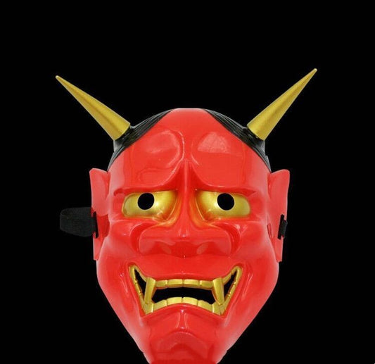 A red demon mask with exaggerated features, including yellow eyes, sharp gold horns, and jagged gold teeth, set against a black background.