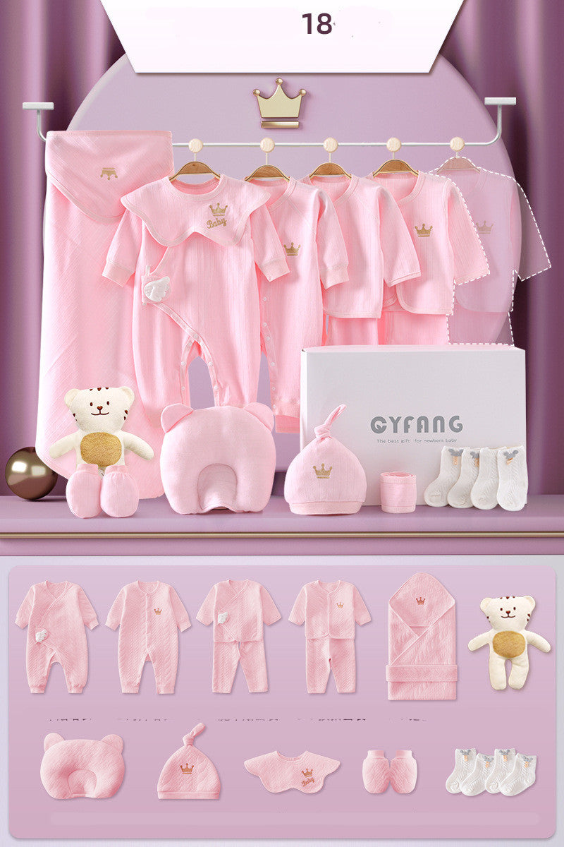 Pink baby clothing set includes onesies, jackets, hats, socks, a swaddle, plush bear, and other accessories displayed attractively with gold crown details on a purple backdrop.