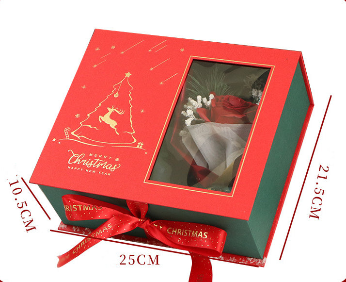 Red and green Christmas gift box with dimensions 25cm x 21.5cm x 10.5cm. Features a clear window, gold tree design, and red ribbon, holding a red rose and small white flowers.