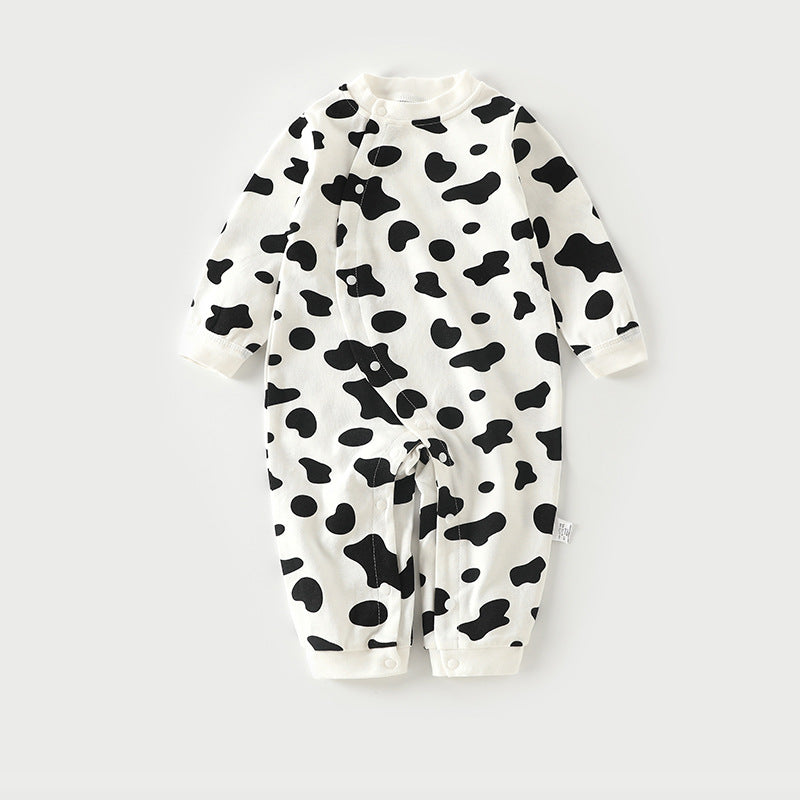 White baby romper with black cow print patterns, featuring long sleeves and a row of buttons down the front for easy closure.
