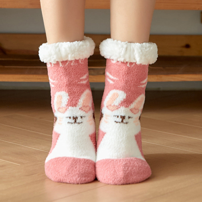 Cozy pink and white socks with a fluffy cuff and cartoon animal face pattern, being worn by someone standing on a wooden floor.