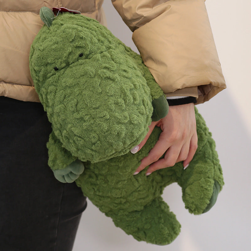 A person in a beige jacket holds a large green crocodile plush toy with curly texture, against a plain background.