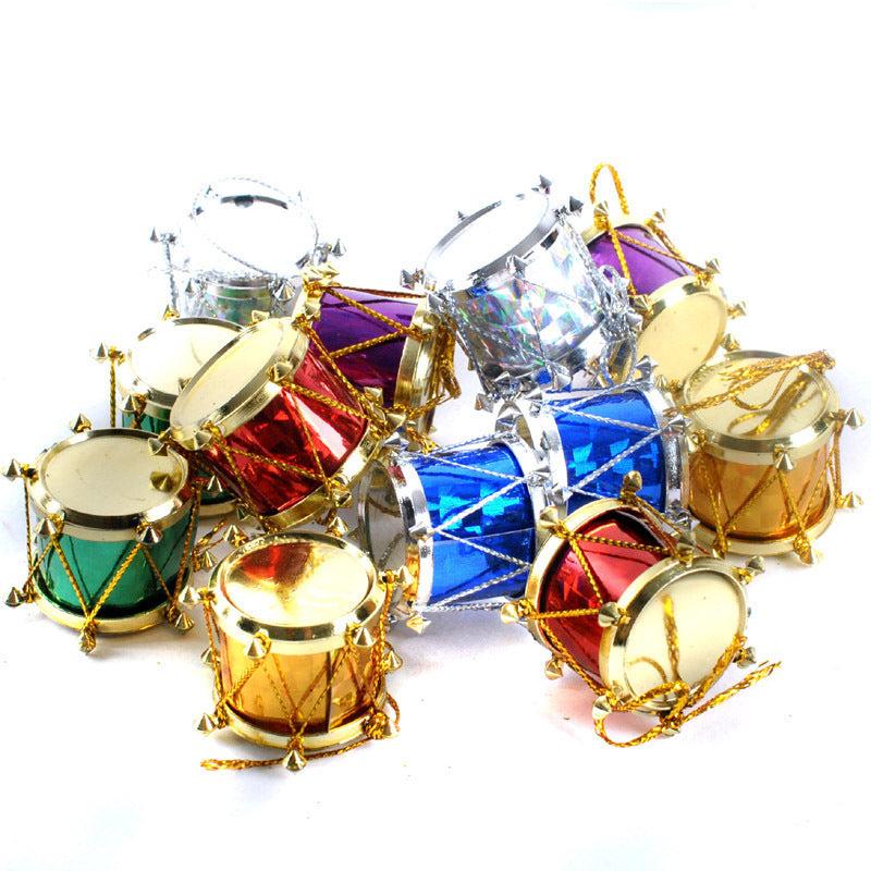 A collection of small, colorful toy drums in metallic red, blue, green, gold, purple, and silver with gold accents and strings, scattered randomly on a white surface.