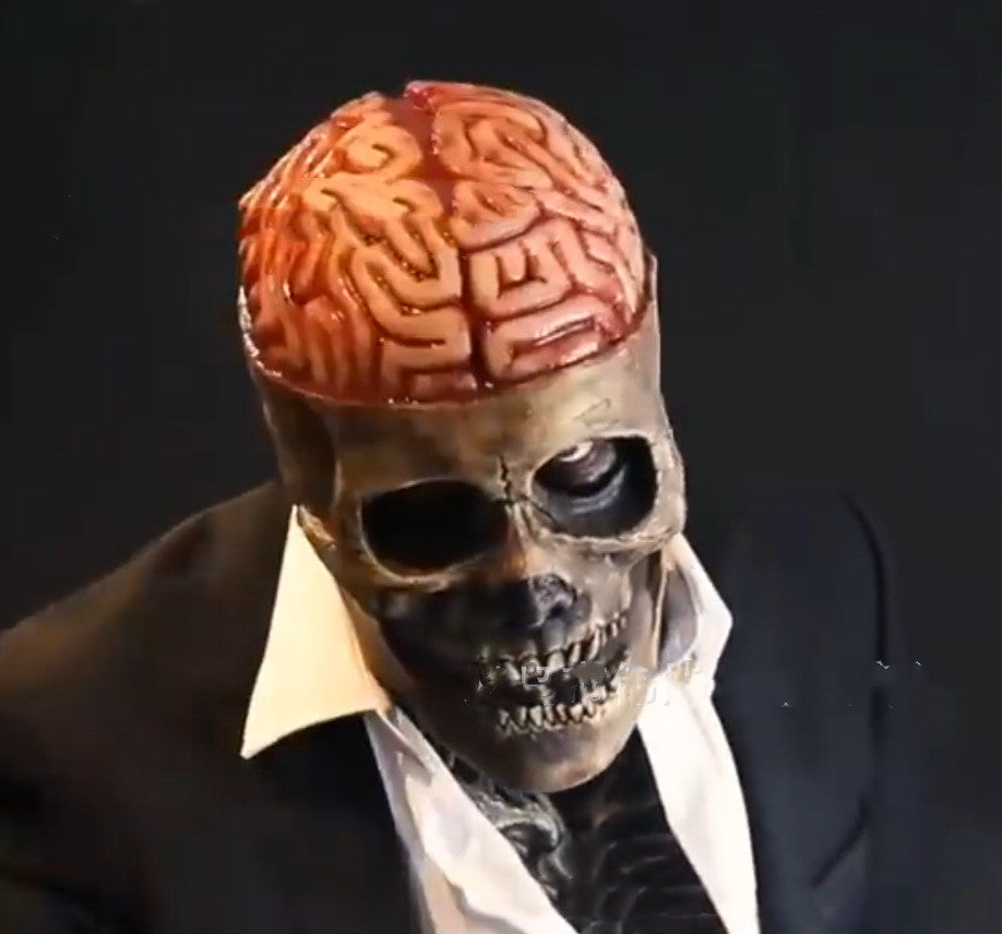 Close-up of a figure in a suit with a realistic skull mask and exposed brain, set against a dark background. The mask features detailed bone and teeth, enhancing the eerie effect.