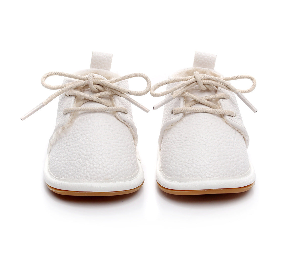 White baby shoes with textured leather surface and lace-up closure, designed with a small heel tab and light brown soles, positioned directly facing the viewer.