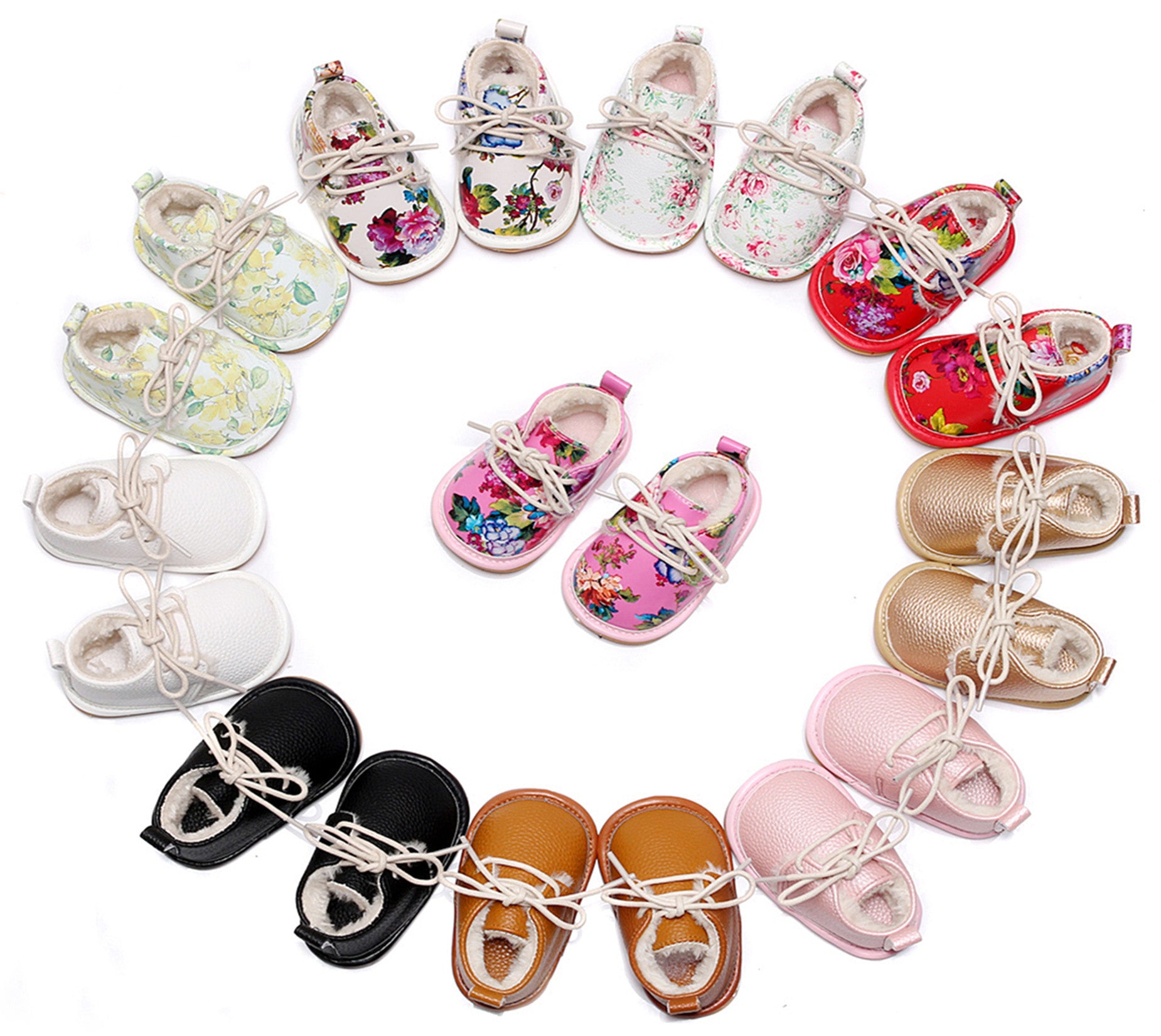 A circle of colorful baby shoes with floral, solid white, black, tan, pink, and metallic gold designs. In the center, pink floral shoes complete the arrangement.