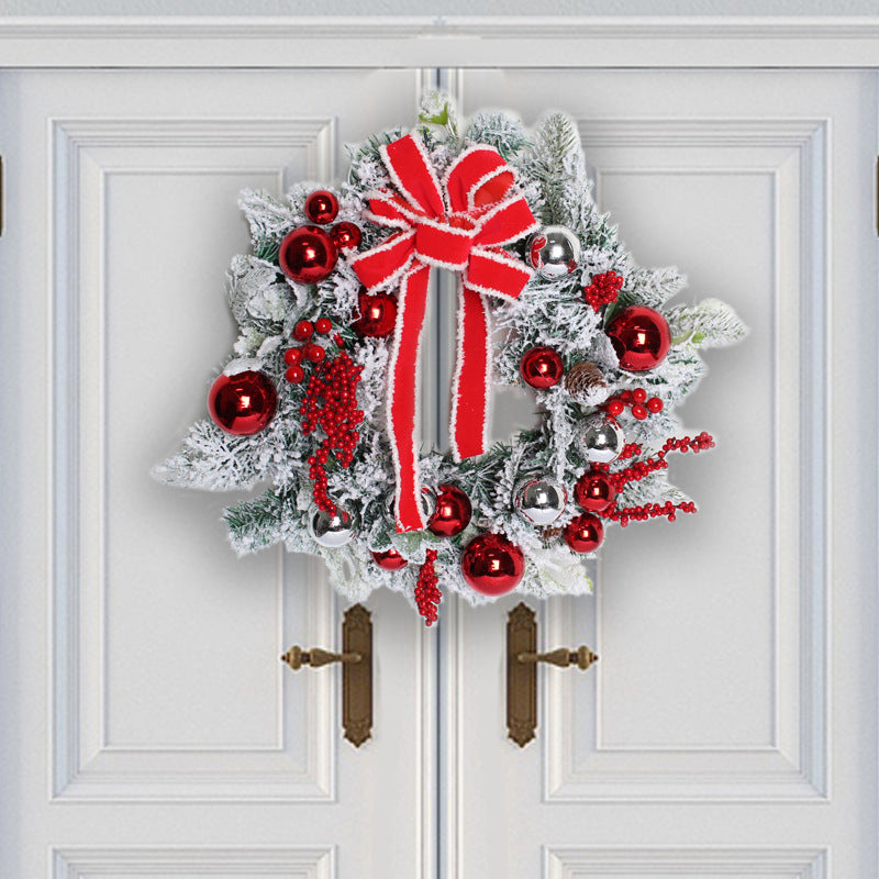 Festive wreath with red and silver ornaments, frosted greenery, and a large red bow, hanging on double white doors.