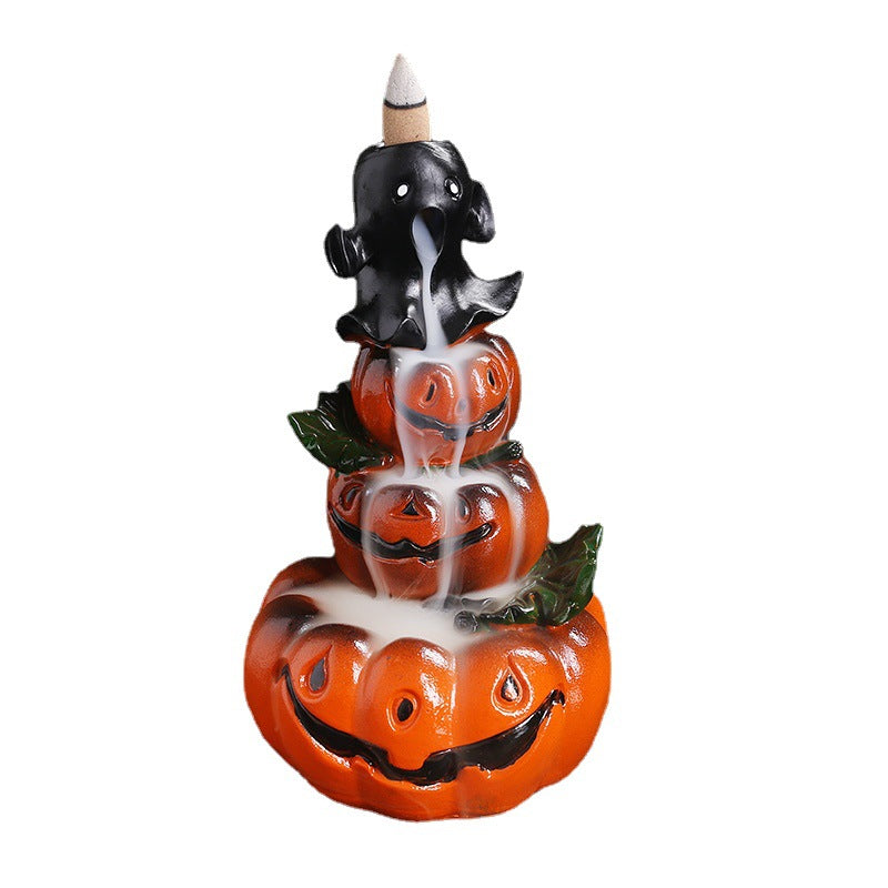 Halloween-themed incense burner with a black ghost atop three stacked, grinning orange pumpkins. White smoke flows downward, creating a spooky cascade effect.