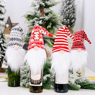 Festive gnome decorations with long white beards and colorful hats adorn wine bottles, set against a background of snowy evergreen branches and holiday decor.