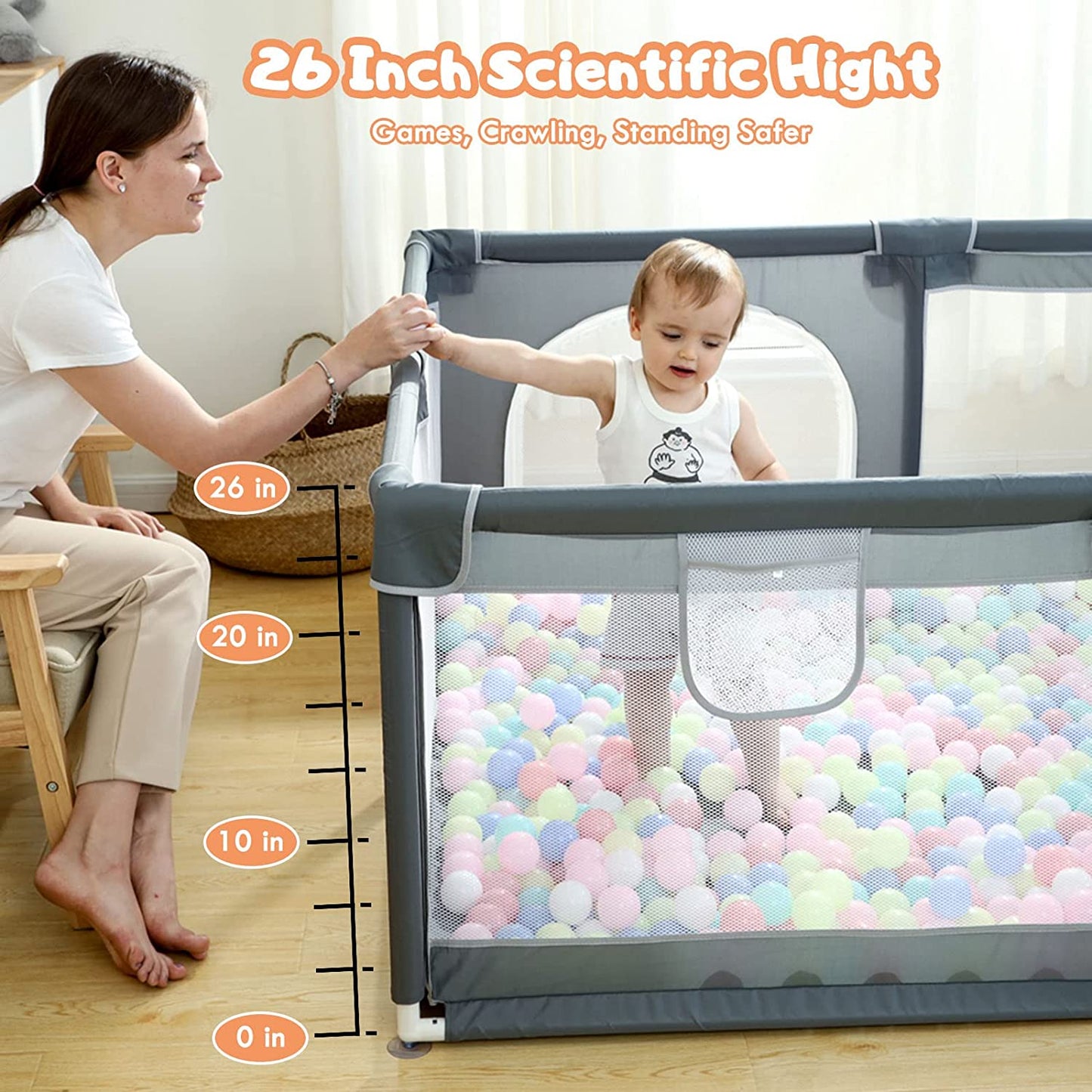 A toddler in a playpen filled with colorful balls holds a woman's hand. The playpen height is labeled as 26 inches, ensuring safety for games, crawling, and standing.