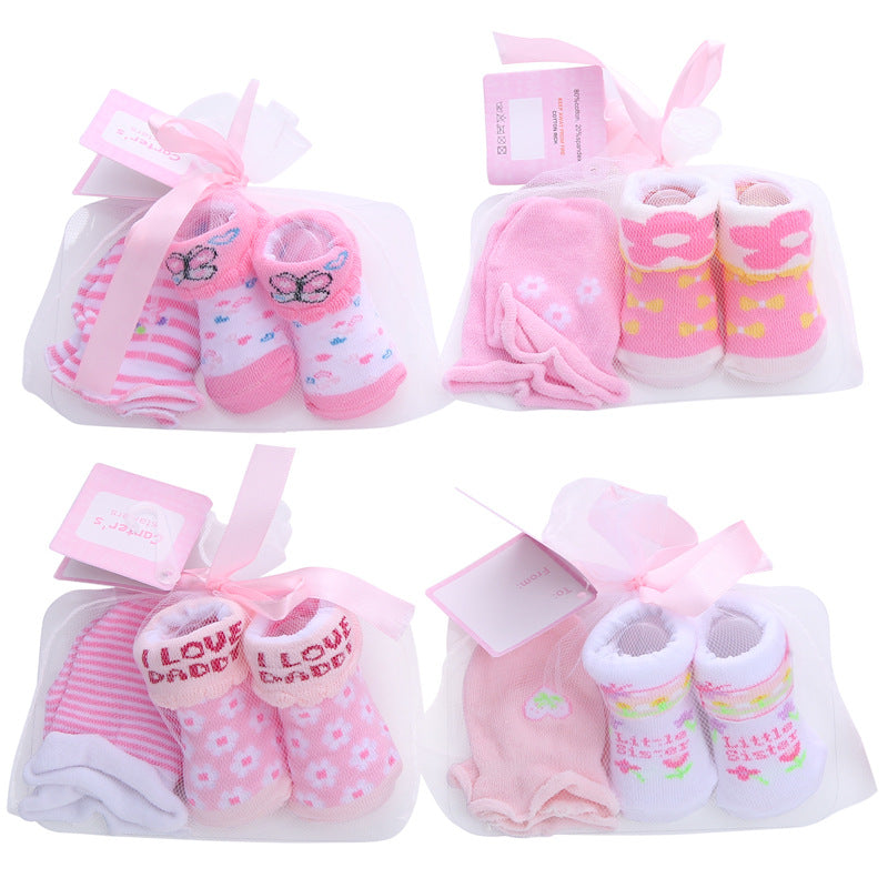 Four sets of pink baby socks and mittens, each with different patterns like butterflies, stripes, and floral designs. Each set is tied with a pink ribbon and tagged.