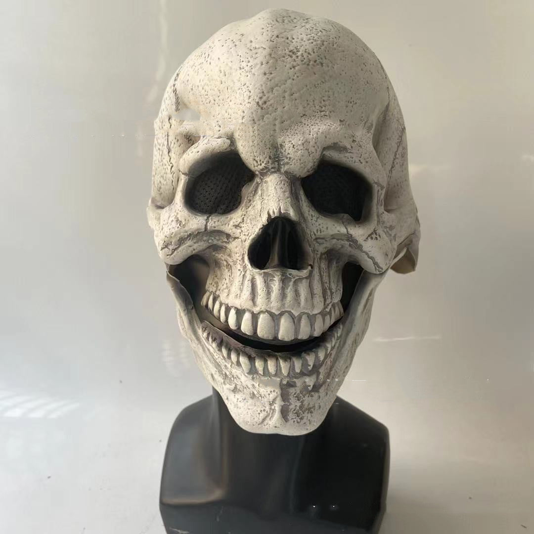 A detailed, realistic-looking skull mask with a slightly open mouth and textured surface, displayed on a black stand against a plain background.
