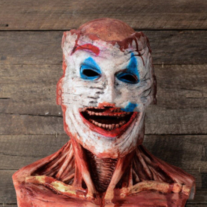 Creepy anatomical bust with exposed muscles and a clown face painted on raw skin. Distressed eyes and mouth create an unsettling expression against a wooden background.