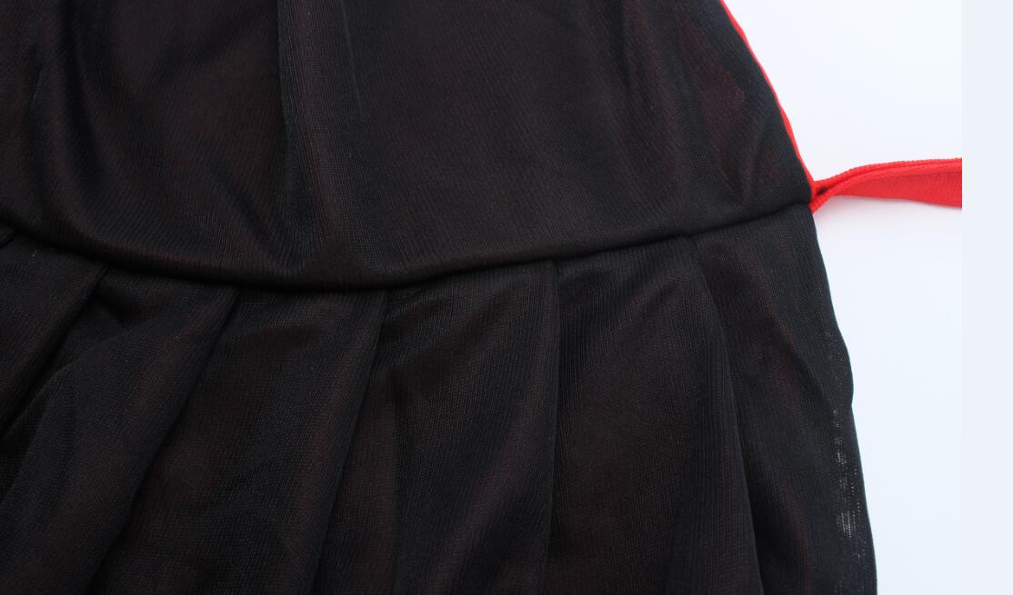Close-up of a black pleated fabric with a red strap on the side, showing texture and structure. The background is white for contrast.