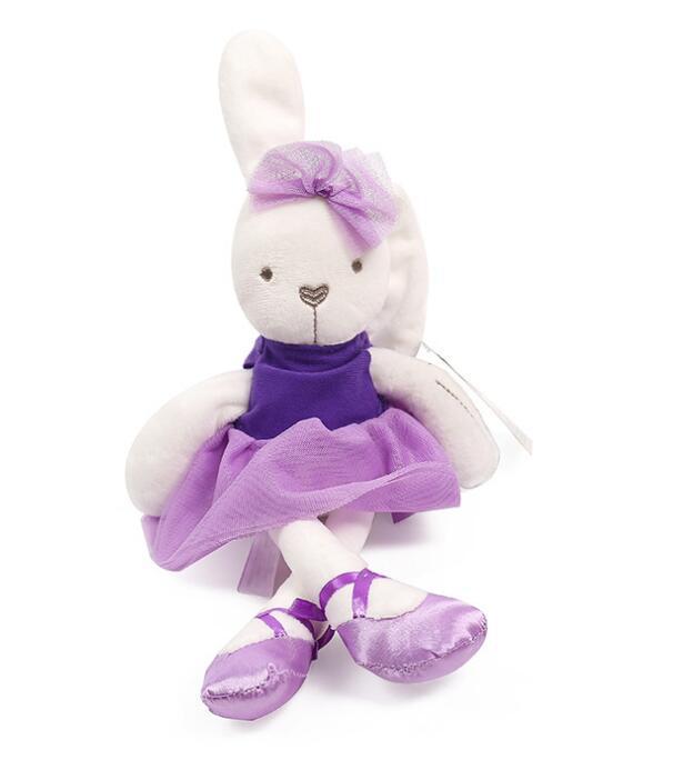 Plush bunny wearing a purple tutu and ballet shoes, sitting with legs crossed. The bunny has a bow on one ear and an embroidered face, set against a plain white background.