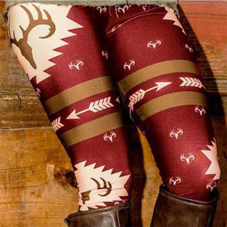 Maroon leggings with a white and brown pattern featuring deer antlers and arrows, paired with brown boots. The background is wooden panels.