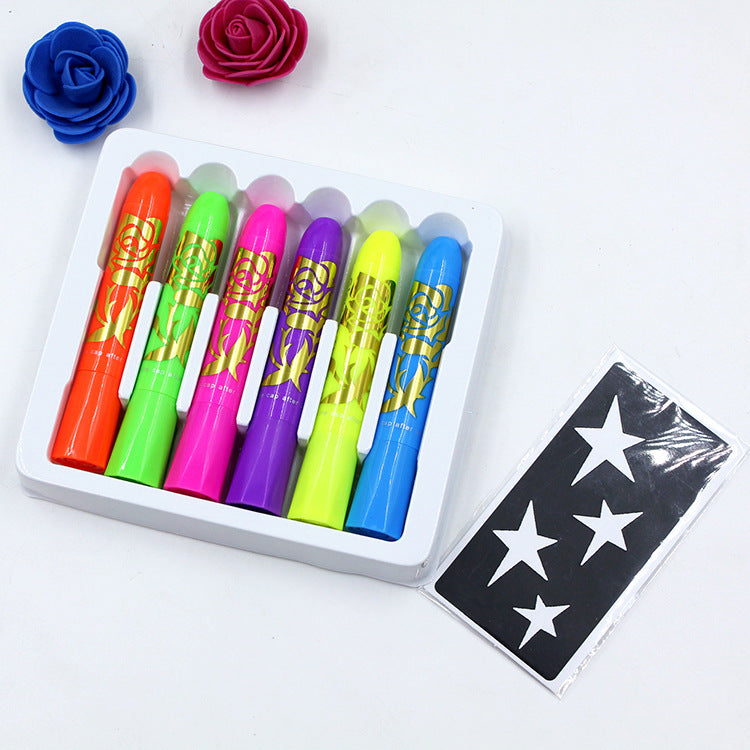 Six colorful, rose-patterned wax crayons in a white tray with a star stencil sheet. Blue and red decorative rose-shaped items are placed nearby.