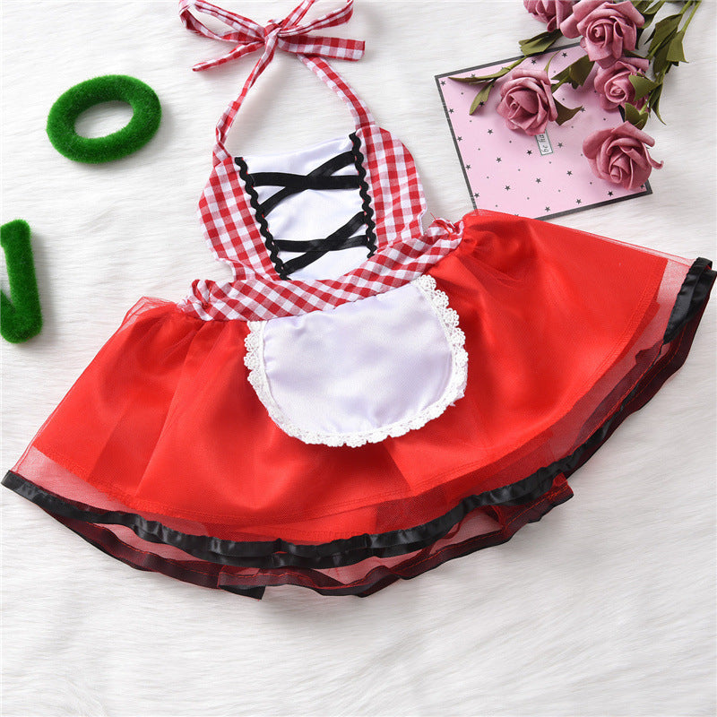 Red and white checkered gingham dress with a black tie detail and lace-trimmed white apron, displayed on a white background, next to a pink notebook and roses.