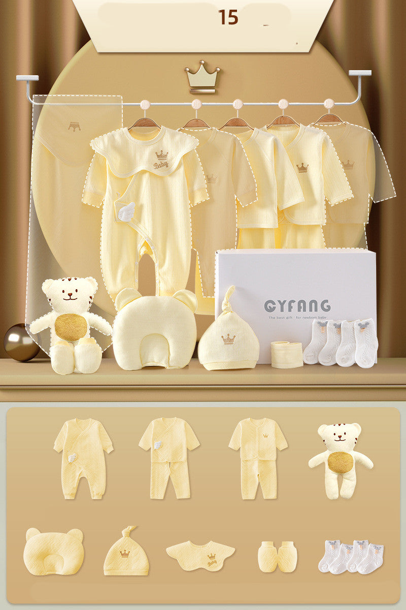 Yellow baby clothing set including rompers, shirts, pants, hat, bib, and socks with bear designs. Displayed on a golden background with a plush bear toy and gift box.