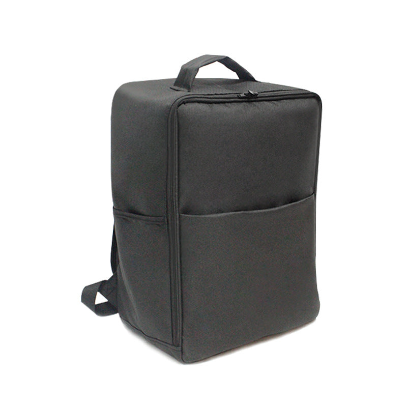 A black, rectangular backpack with a top handle and side pocket. The design is sleek and minimalist, with a zipper on top and adjustable shoulder straps visible from the side angle.