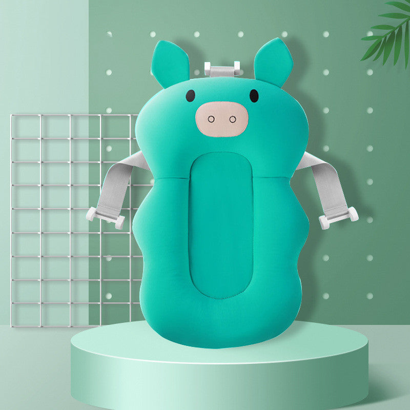 Teal pig-shaped baby bath seat with adjustable straps on a green background, featuring a grid and plant accents.