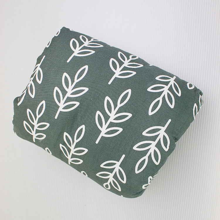 A gray pillow with a white leaf pattern on a light background, featuring simple branch designs repeated evenly across the fabric.