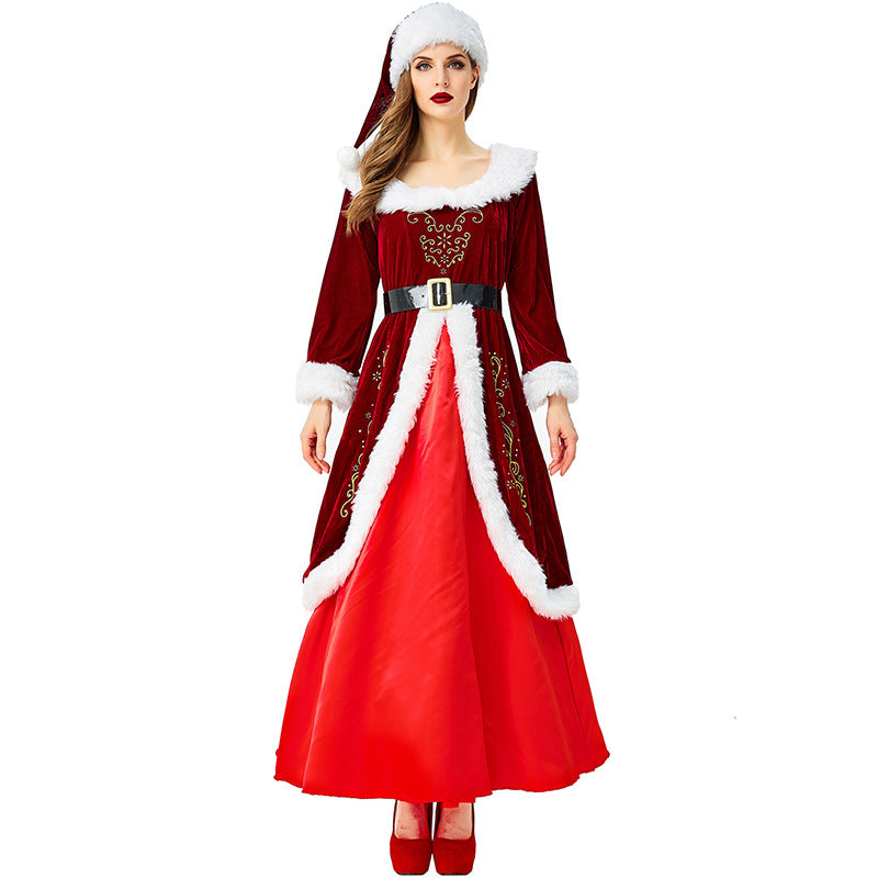 Woman in a festive red velvet Santa dress with white fur trim, ornate gold embroidery, and black belt, wearing a matching Santa hat and red heels.