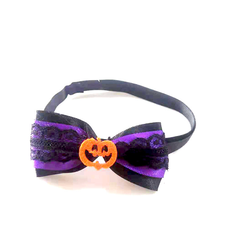 A black and purple lace bow tie with an orange Jack-o'-lantern centerpiece, attached to a black strap, evokes a festive Halloween theme.