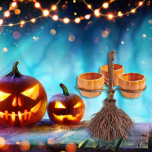 Halloween scene with glowing jack-o'-lanterns on a wooden surface, fairy lights above, and a decorative broom holding pumpkin-shaped holders against a vibrant blue background.