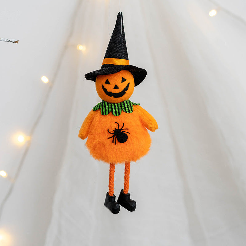 Plush pumpkin figurine with a witch hat hangs against a light backdrop. It features a jack-o'-lantern face, green collar, and spider design, with rope legs and black shoes.