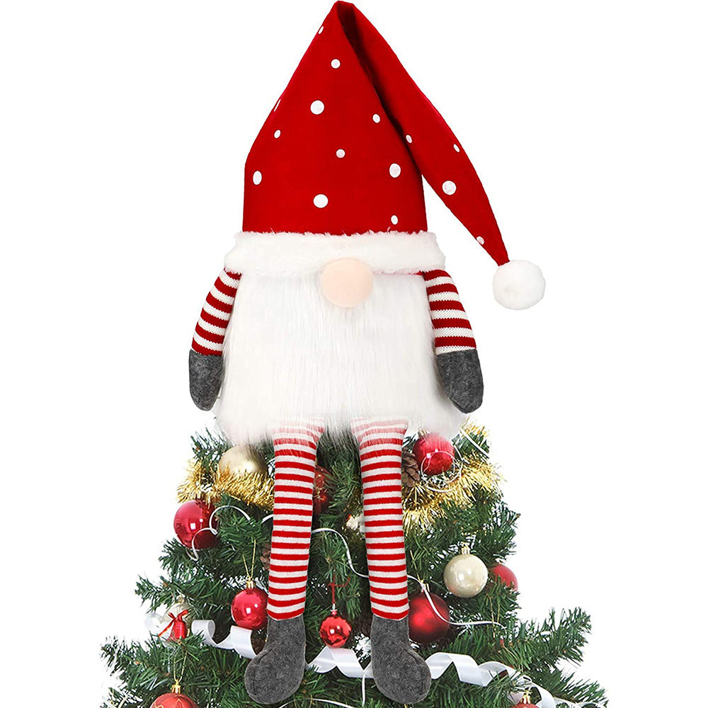 Christmas tree topped with a plush gnome. The gnome wears a red hat with white polka dots, has striped red and white arms and legs, and sits among red and gold baubles.