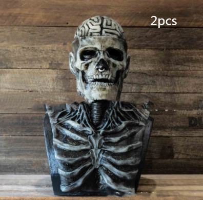 A skeletal bust with brain patterns on the skull sits on a wooden surface against a wood-paneled background. "2pcs" is written in the top right corner.