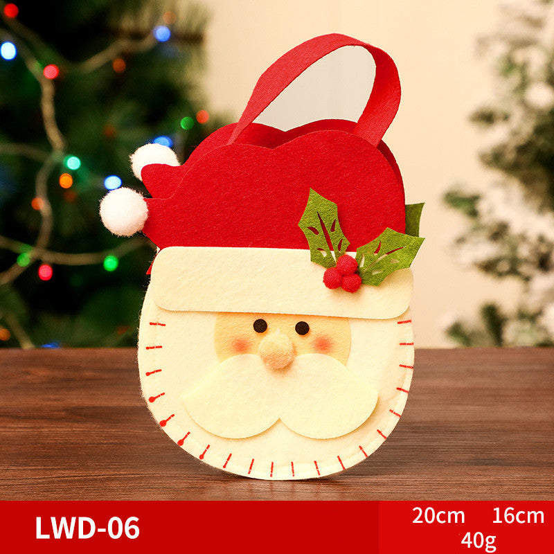 A felt Santa Claus gift bag with a red hat and holly design. It is placed on a wooden surface with a blurred Christmas tree background. Size details: 20cm x 16cm, 40g.