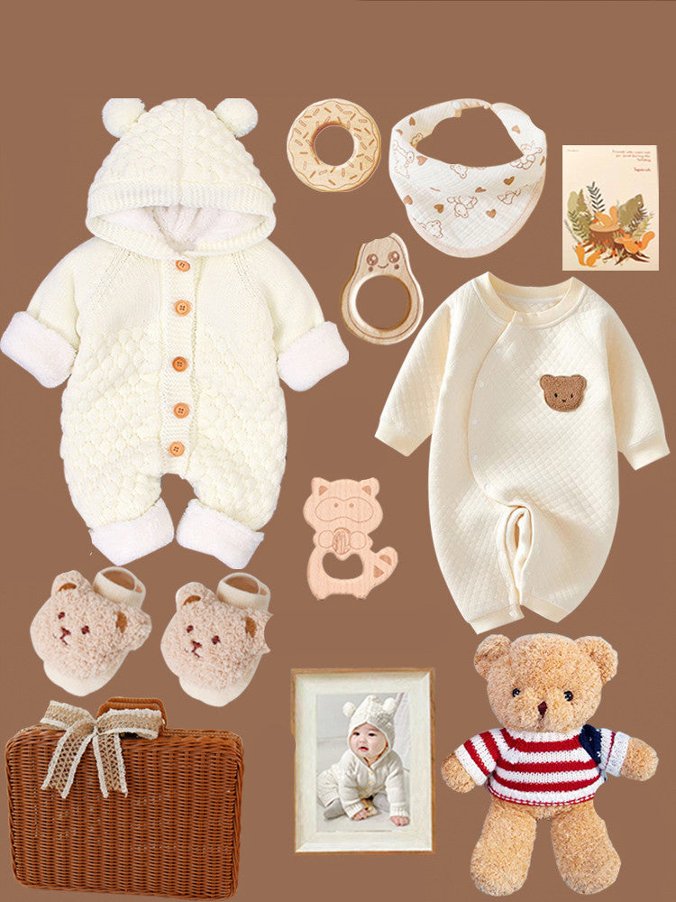 Baby gift set on a brown background, includes a white hooded onesie, cream romper, teething rings, bib, teddy bear, baby booties, wicker basket, and a framed baby photo.