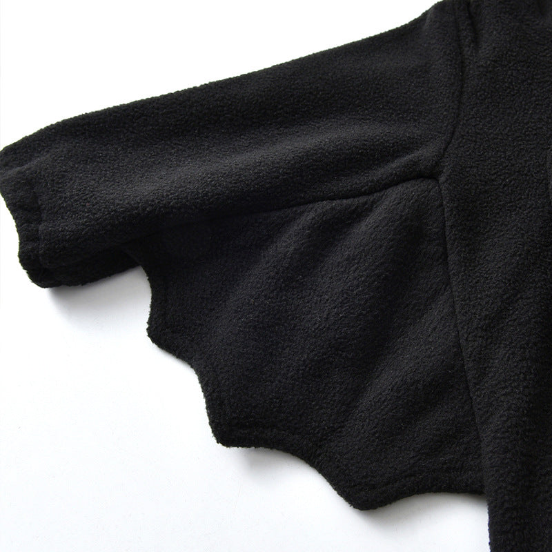Close-up of a black garment with a textured fabric and a uniquely shaped sleeve that resembles a bat wing, showcasing its detailed construction and design.