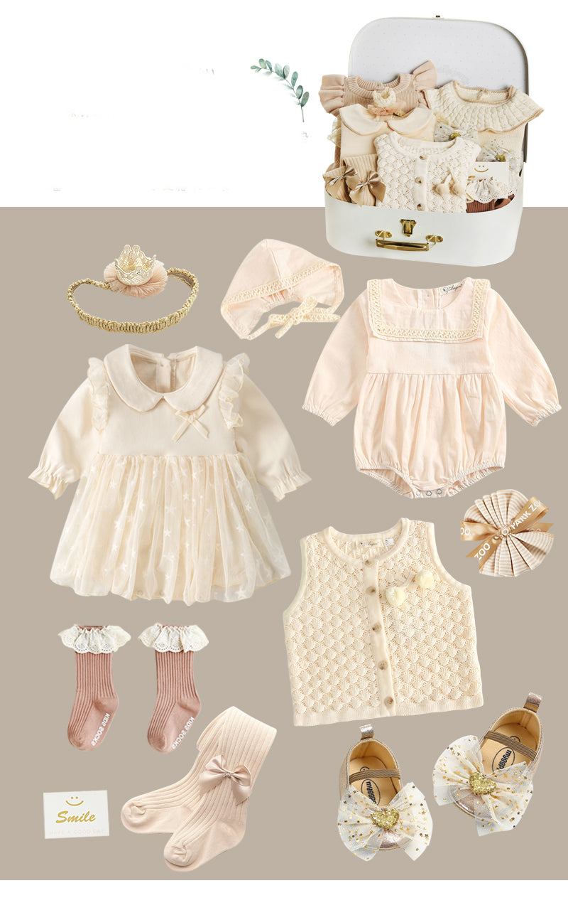 A collection of pastel baby outfits includes dresses, rompers, booties, socks, vests, and headbands. Accessories like a suitcase, ribbon, and "Smile" card are also featured.