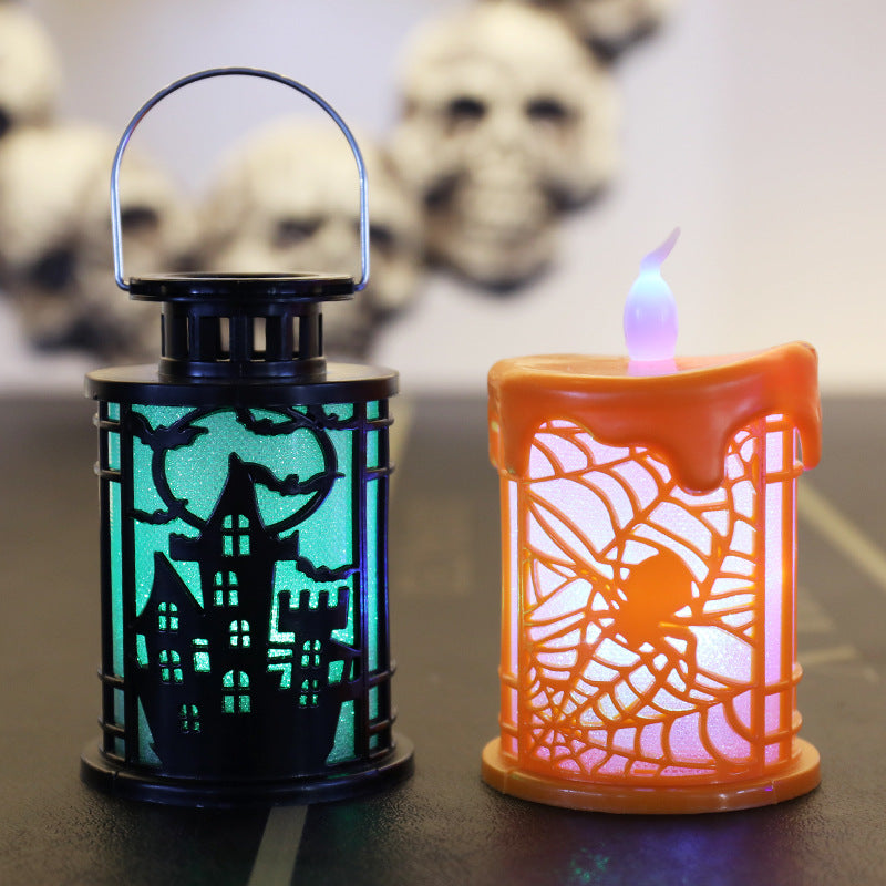 Two Halloween-themed lanterns on a table. The left lantern is black with a silhouette of a haunted house and bats against a glowing green background. The right lantern is orange, shaped like a melting candle with a spider web design, glowing purple. Blurry skulls are visible in the background.