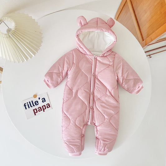 Pink quilted baby snowsuit with bear ears on the hood, displayed on a white circular table next to a folded paper lamp and a card with text "fille' a papa".