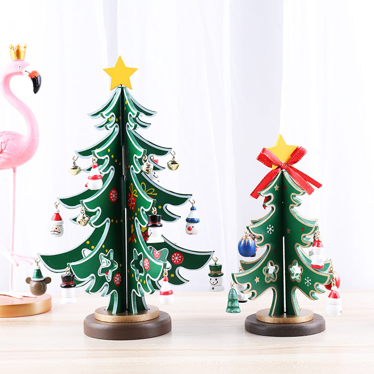 Two small decorative Christmas trees with ornaments, stars on top, and a pink flamingo figurine in the background, set on a light-colored surface.