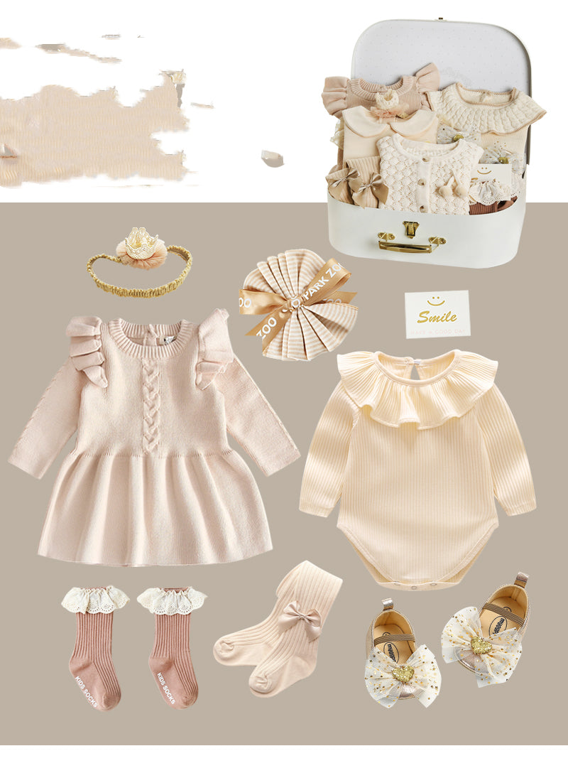 Baby clothing set includes a beige dress, cream bodysuit, socks with lace trim, headband, shoes with bows, and a decorative gift box with "Smile" card, all in soft pastel colors.
