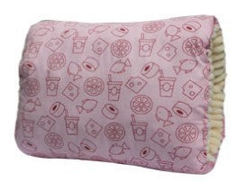 Pink cushion with red patterns of doughnuts, drinks, and geometric shapes. Cream-colored ruffled edging adds texture to the side.