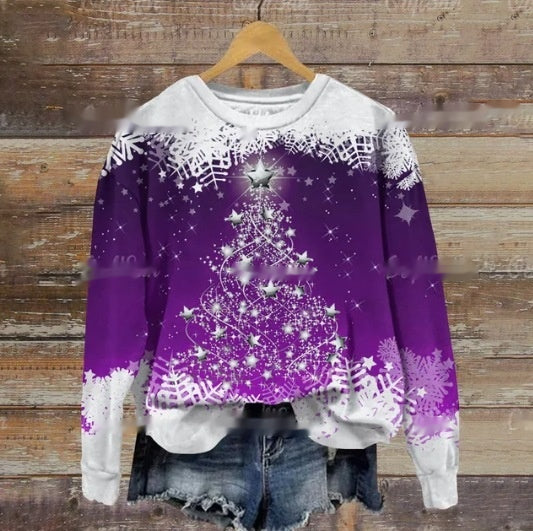 Purple and white sweater with a glittering Christmas tree, topped with a star, surrounded by snowflakes. Displayed on a hanger with distressed denim shorts against a wooden background.