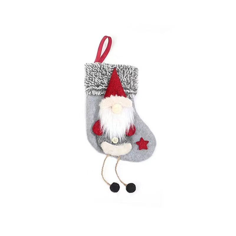 Gray Christmas stocking with a plush gnome design featuring a red hat and star, white beard, and dangling legs with black pom-poms, and a red hanging loop at the top.