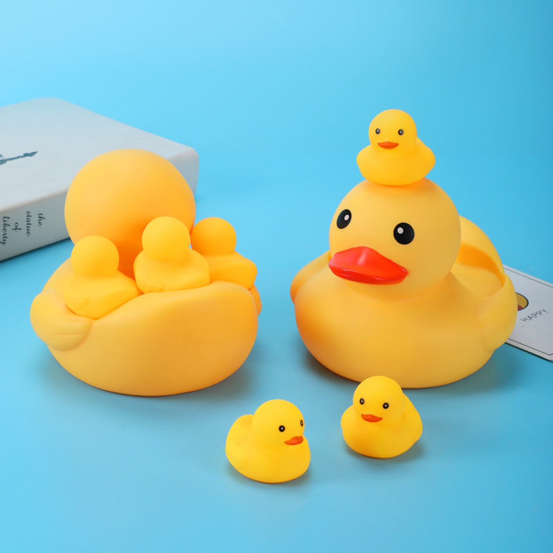 Yellow rubber duck set on a blue background, featuring a large duck with smaller ducklings inside and around it. A stack of books is partially visible in the background.