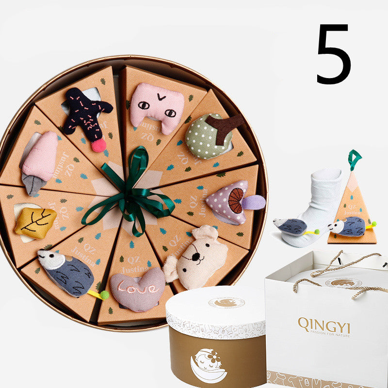 Round gift box with wedge-shaped compartments, each topped with a cute plush charm like a bear or hedgehog. Includes a white sock set. Packaging labeled "Qingyi."