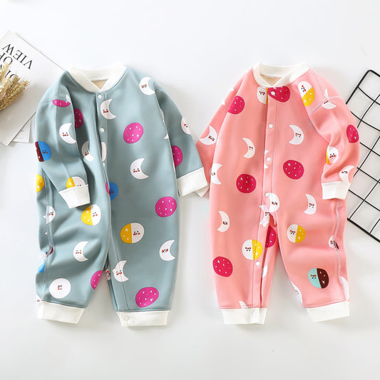 Two baby onesies on a flat lay: one blue with moon and circle patterns, and one pink with similar designs. Both have snap buttons and white cuffs on a white background.