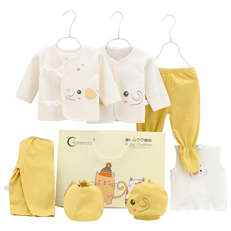 Baby clothing set in white and yellow includes two tops with playful designs, pants, a hat, bib, and mittens. Presented with a gift bag featuring cute animal illustrations.