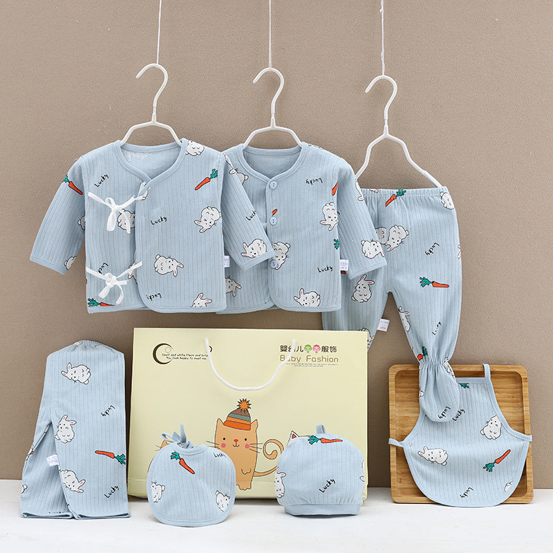 Blue baby clothing set includes two jackets, pants, a bib, hat, mittens, and a burp cloth, all with a cute rabbit and carrot print. Displayed with a gift bag and wooden tray.