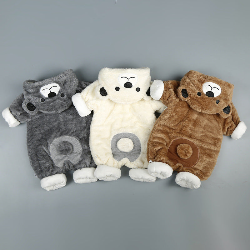 Three plush, bear-shaped baby onesies in gray, beige, and brown are laid side by side on a gray background. Each features a cute bear face on the hood and white cuffs.