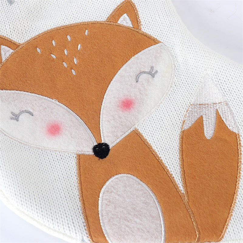 Embroidered fox design on a knitted white fabric, featuring closed eyes, rosy cheeks, and a brown body with white accents, adding a cute and cozy touch.